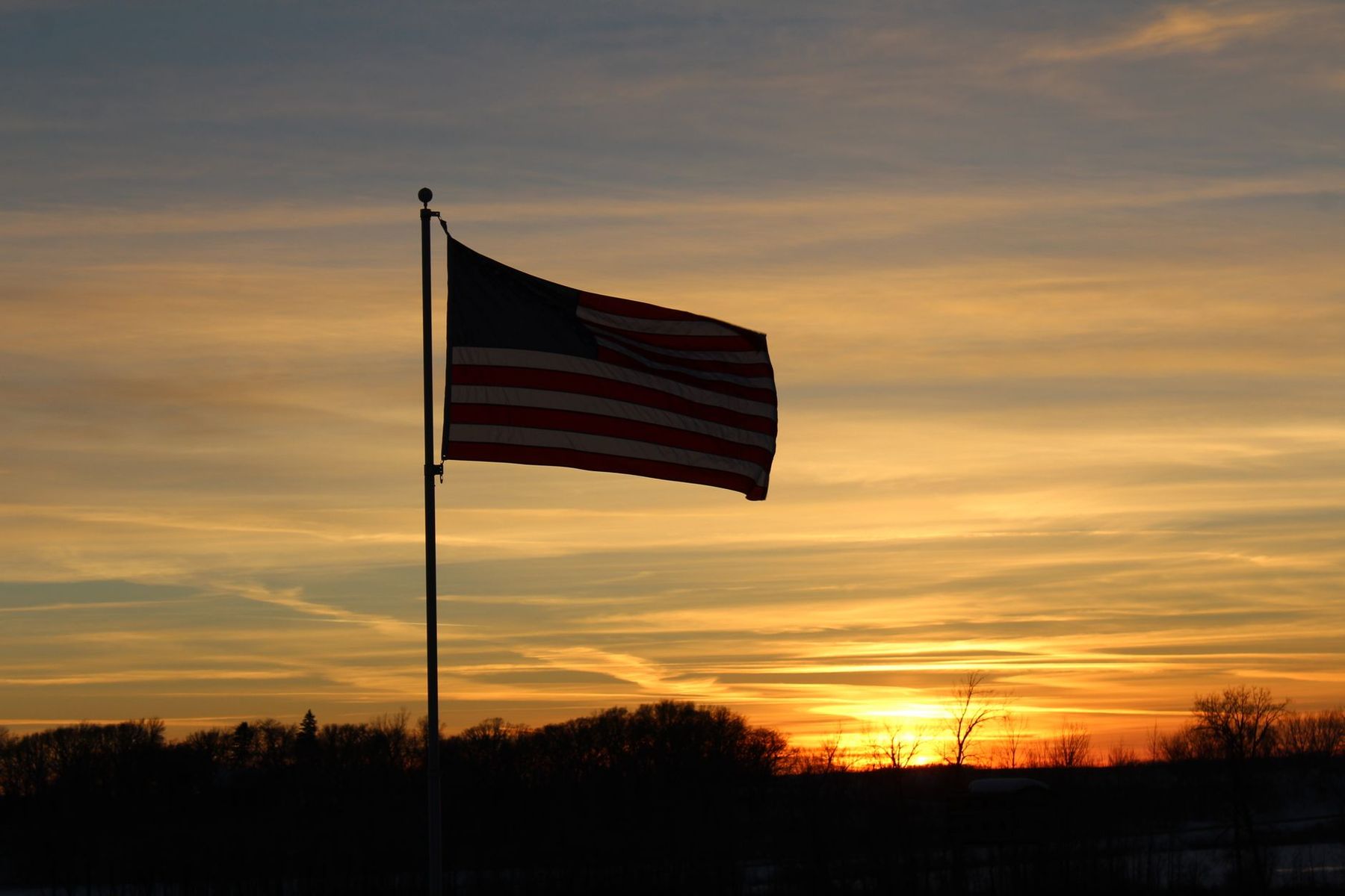 American flag silhouetted against a dusk sky